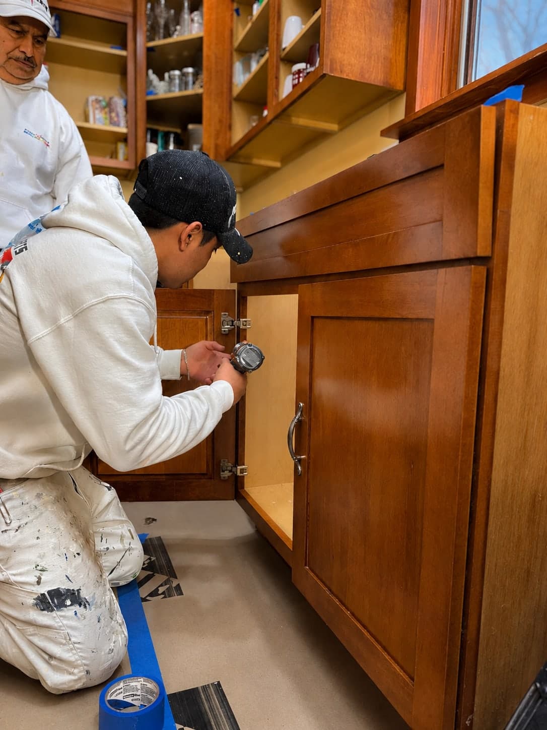 PaintXperts painters refitting hardware to a refinished cabinet door once the finish had cured