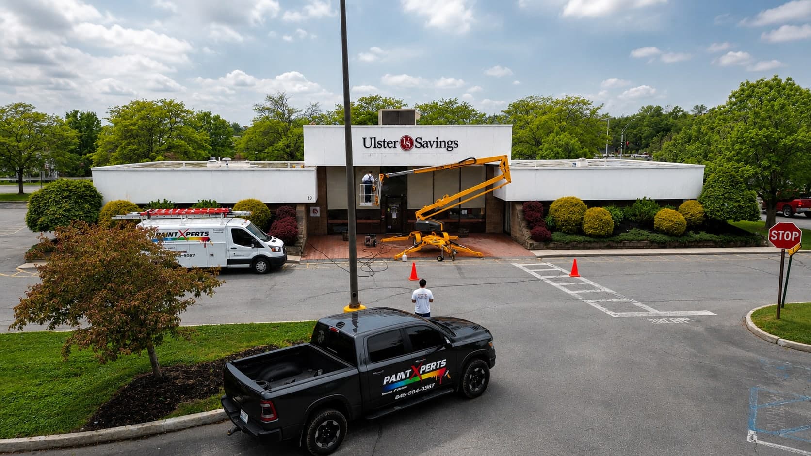 PaintXperts van, pickup and a boom lift on site at an Ulster Savings branch during a commercial repaint